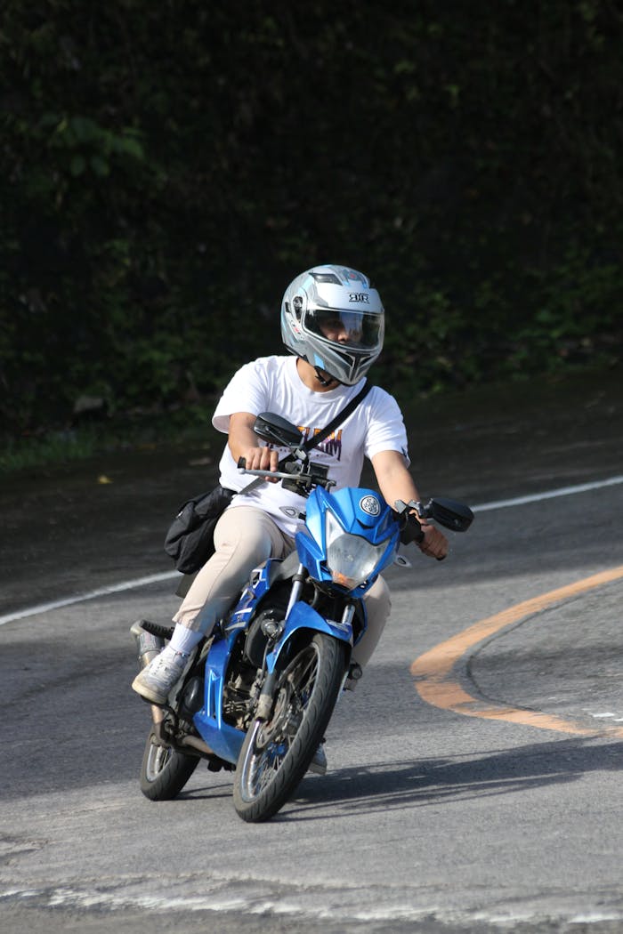 get-in-touch A motorcyclist in protective gear rides a blue motorcycle on a curved road.